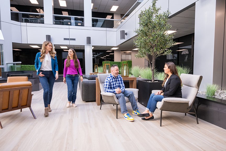 Paradigm marketing team members in shared office lobby standing and sitting in pairs talking