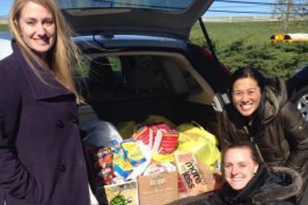 Paradigm team members standing next to car trunk filled with bags of food