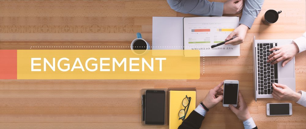 Engagement concept text and three people working on an office table