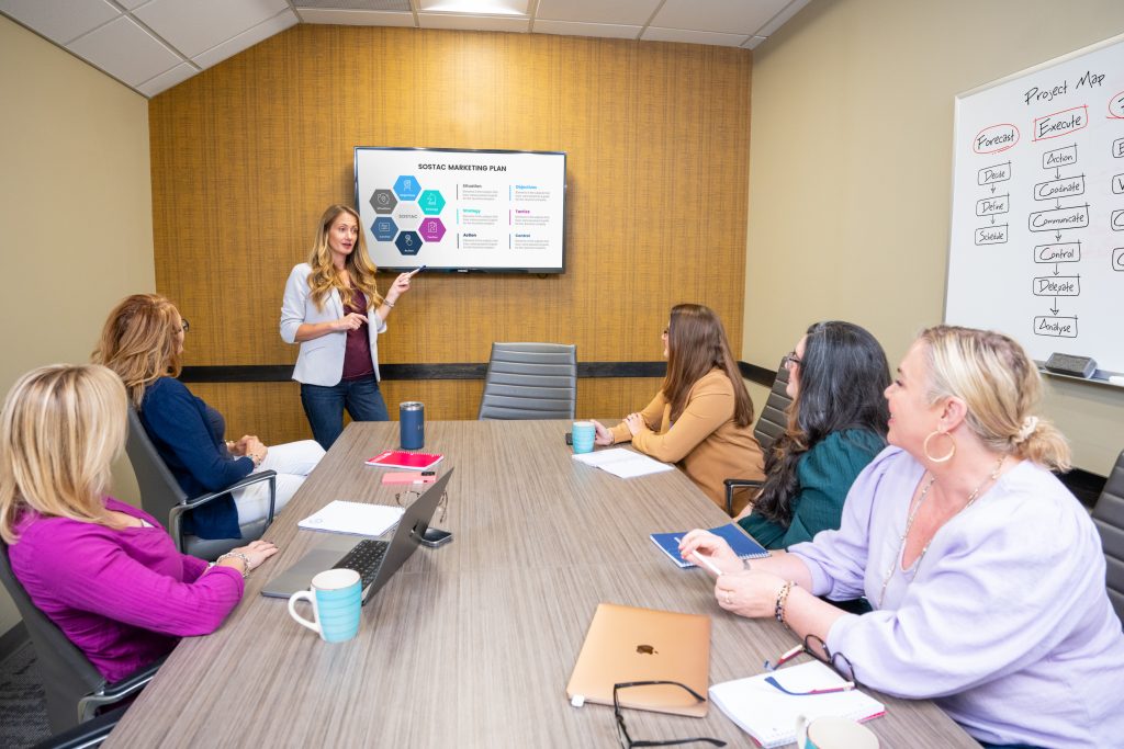 Female marketing professional presenting to conference room of people