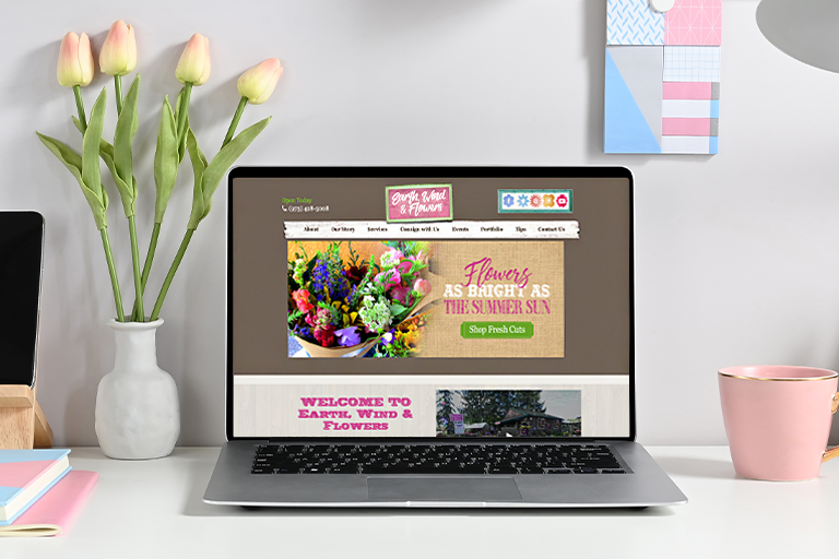 tulips next to a laptop computer featuring Earth Wind and Flowers website